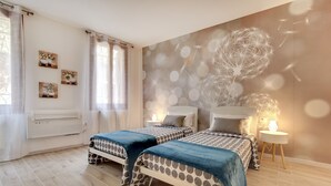 Une chambre avec deux lits, un climatiseur fixé au mur et un mur décoratif orné de motifs abstraits.
