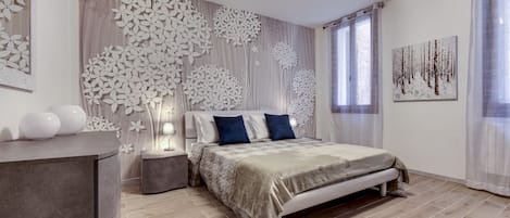 A modern bedroom with a bed, nightstands, a dresser, and decorative wall art.