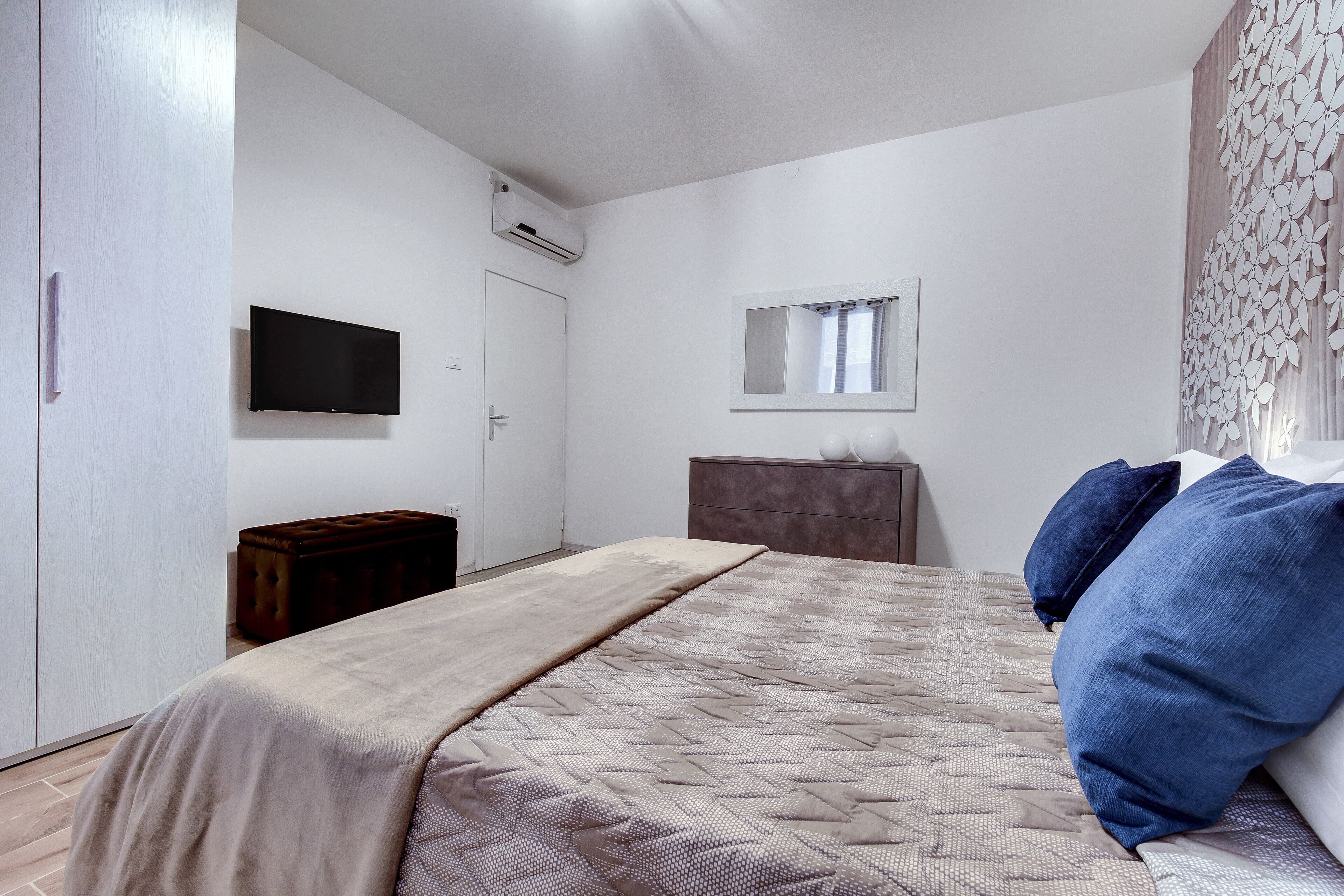 Quarto com uma cama, penteadeira, televisão e guarda-roupa.