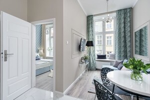 A modern bedroom with a bed, bedside table, and a window with curtains.