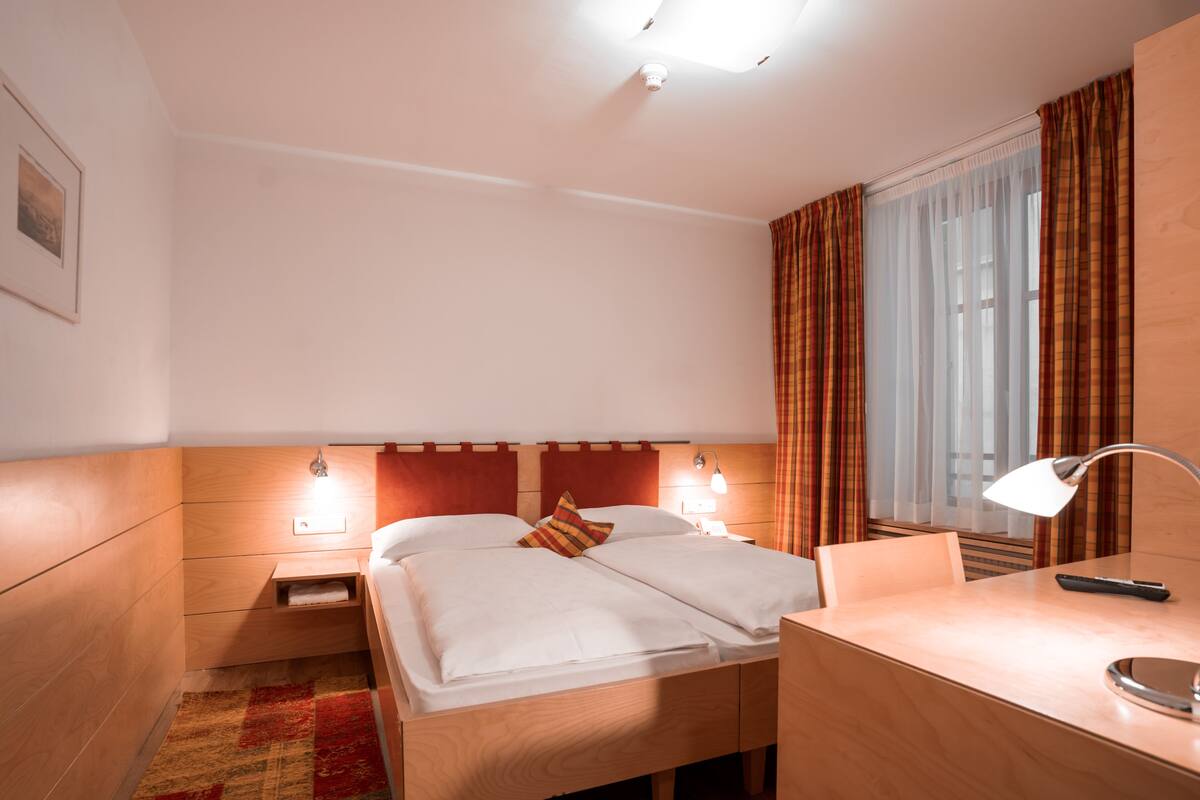 A hotel room with a wooden bed, two bedside tables, a desk, and a chair.