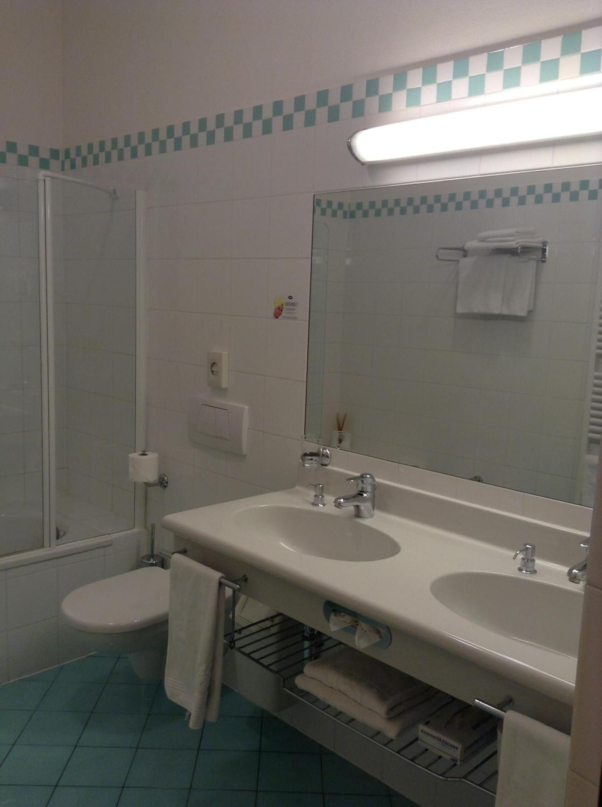 Une salle de bain avec une douche, deux lavabos, des toilettes et un miroir.
