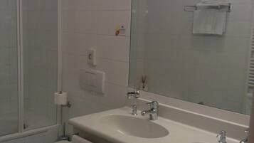 Une salle de bain avec une douche, deux lavabos, des toilettes et un miroir.