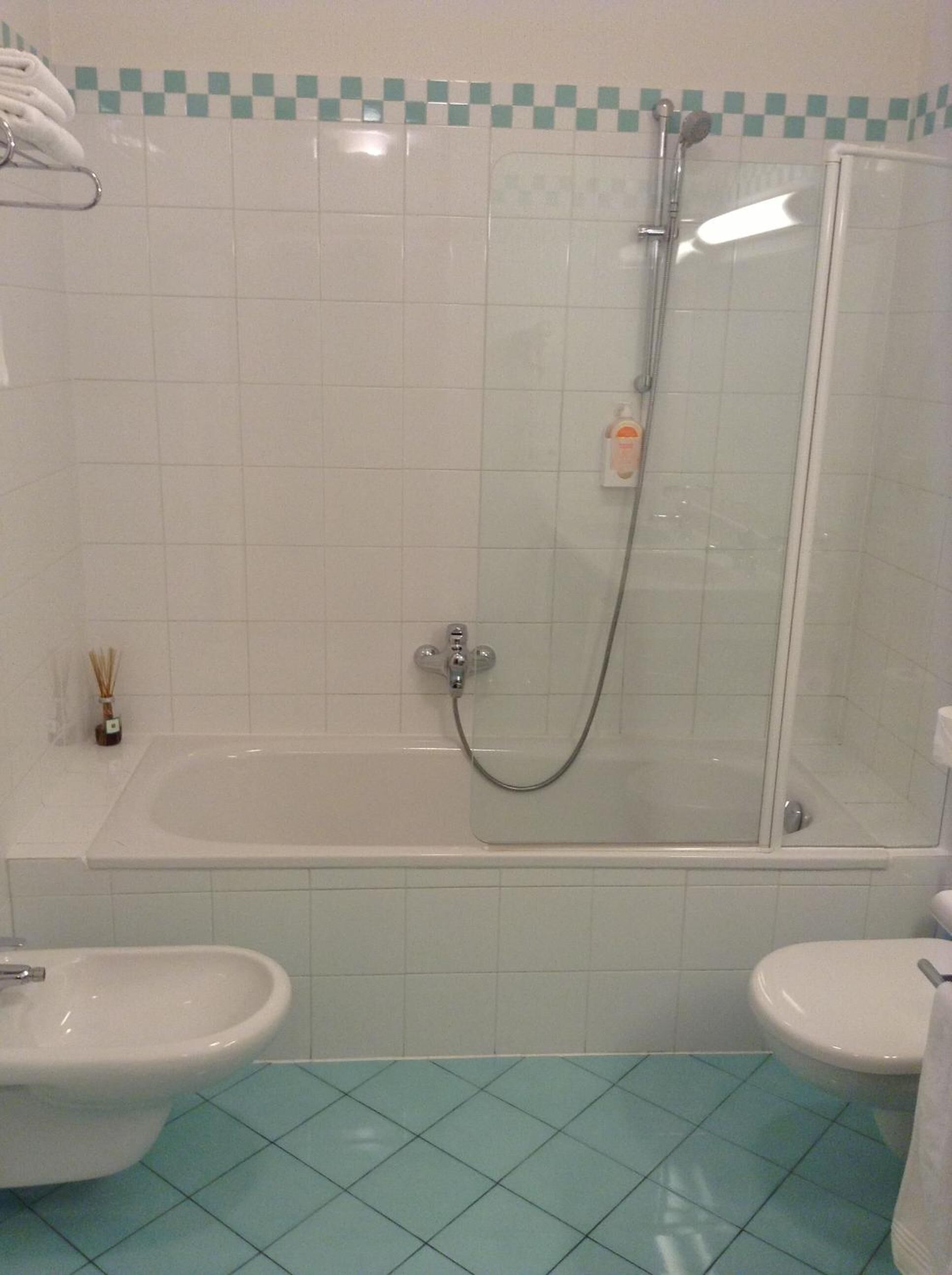 Une salle de bain avec une baignoire, une douche et deux toilettes.