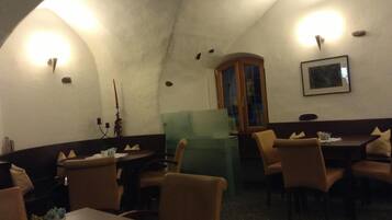 A dimly lit room with arched ceilings, wooden furniture, and a cabinet.