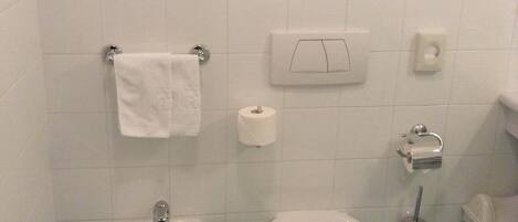 A bathroom with a bidet, a toilet, a sink, and a towel rack.
