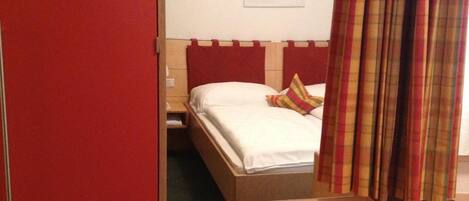 A hotel room with a bed, a small table, and a mirror.