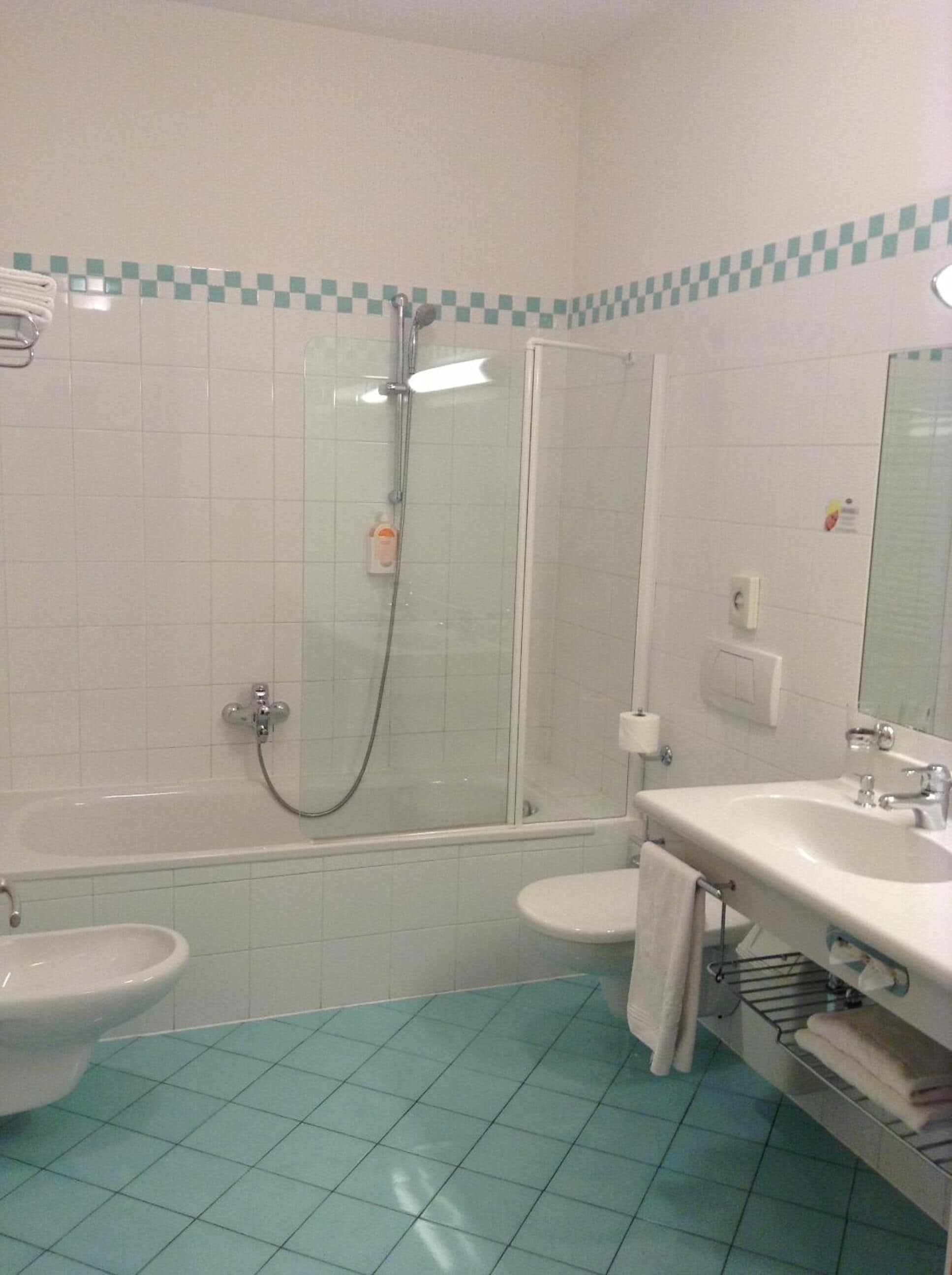 A bathroom with a shower, two sinks, and a toilet.