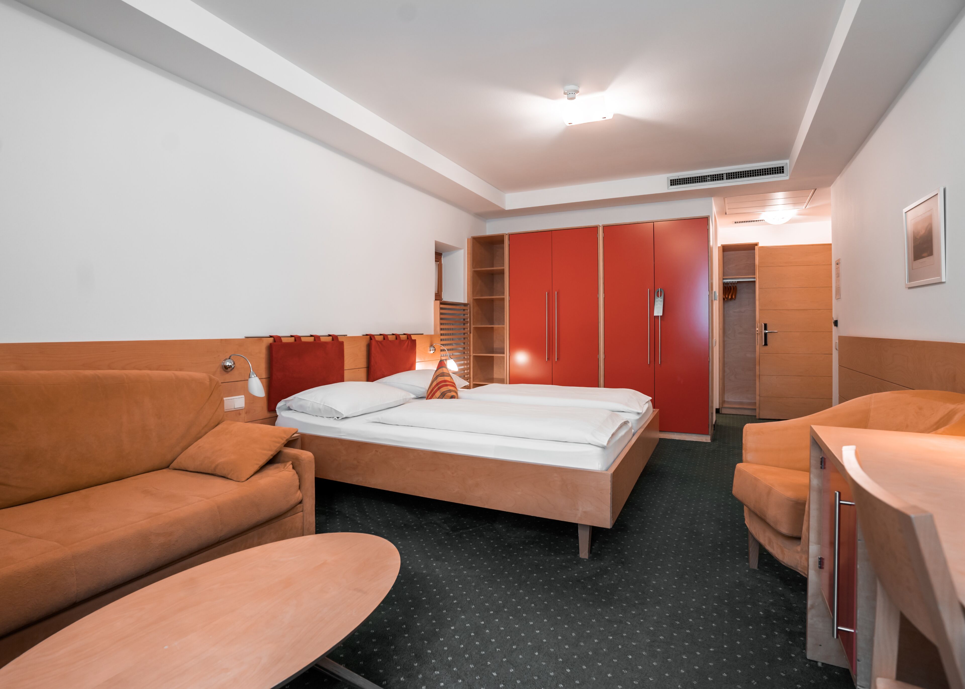 Una habitación de hotel con cama, sofá, escritorio y armario.
