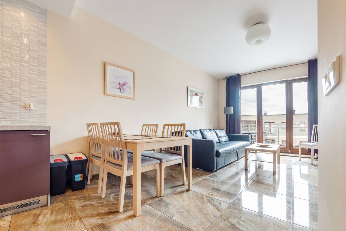 Un appartement moderne comprenant une cuisine, un coin repas et un salon. Il dispose également d’un balcon avec vue.