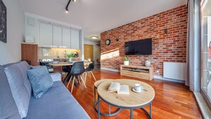 Un salon moderne avec un mur en briques, un téléviseur à écran plat, une table basse en bois et un canapé gris.