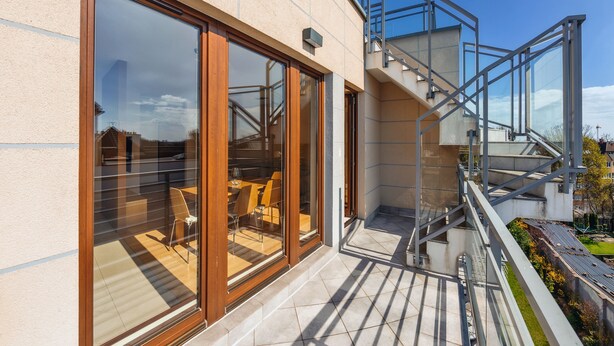 Un bâtiment moderne doté de grandes portes vitrées qui donnent sur un espace extérieur aménagé avec des tables et des chaises.