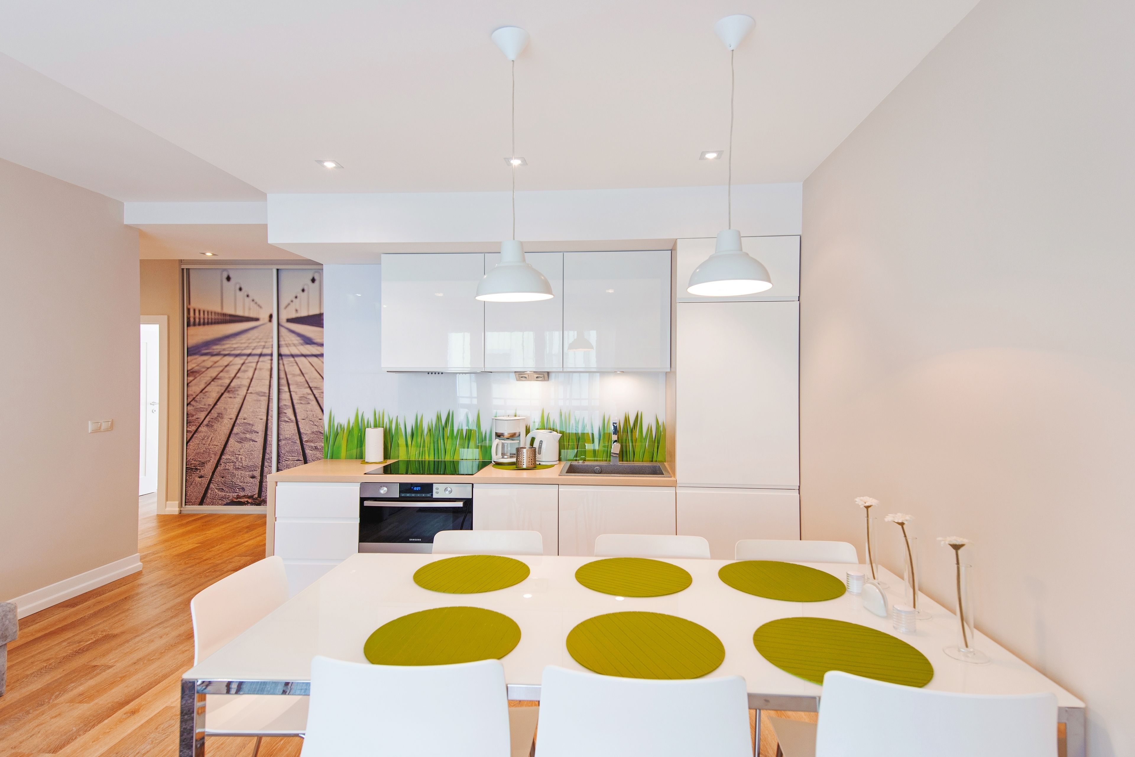 A modern kitchen with white cabinets, a central island, and pendant lighting.