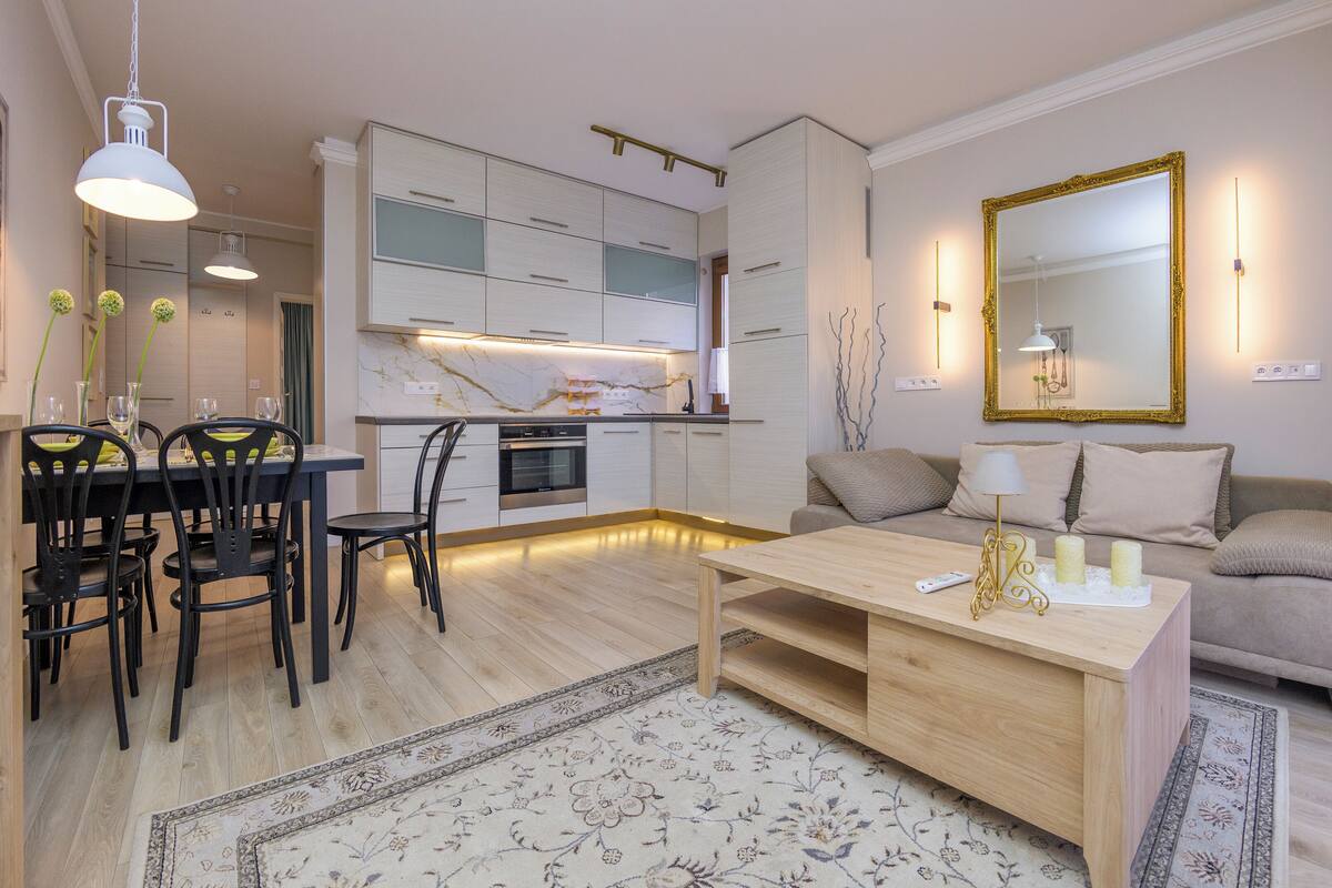 Un salon moderne comprenant un coin repas, un canapé, une table basse et une cuisine en arrière-plan.