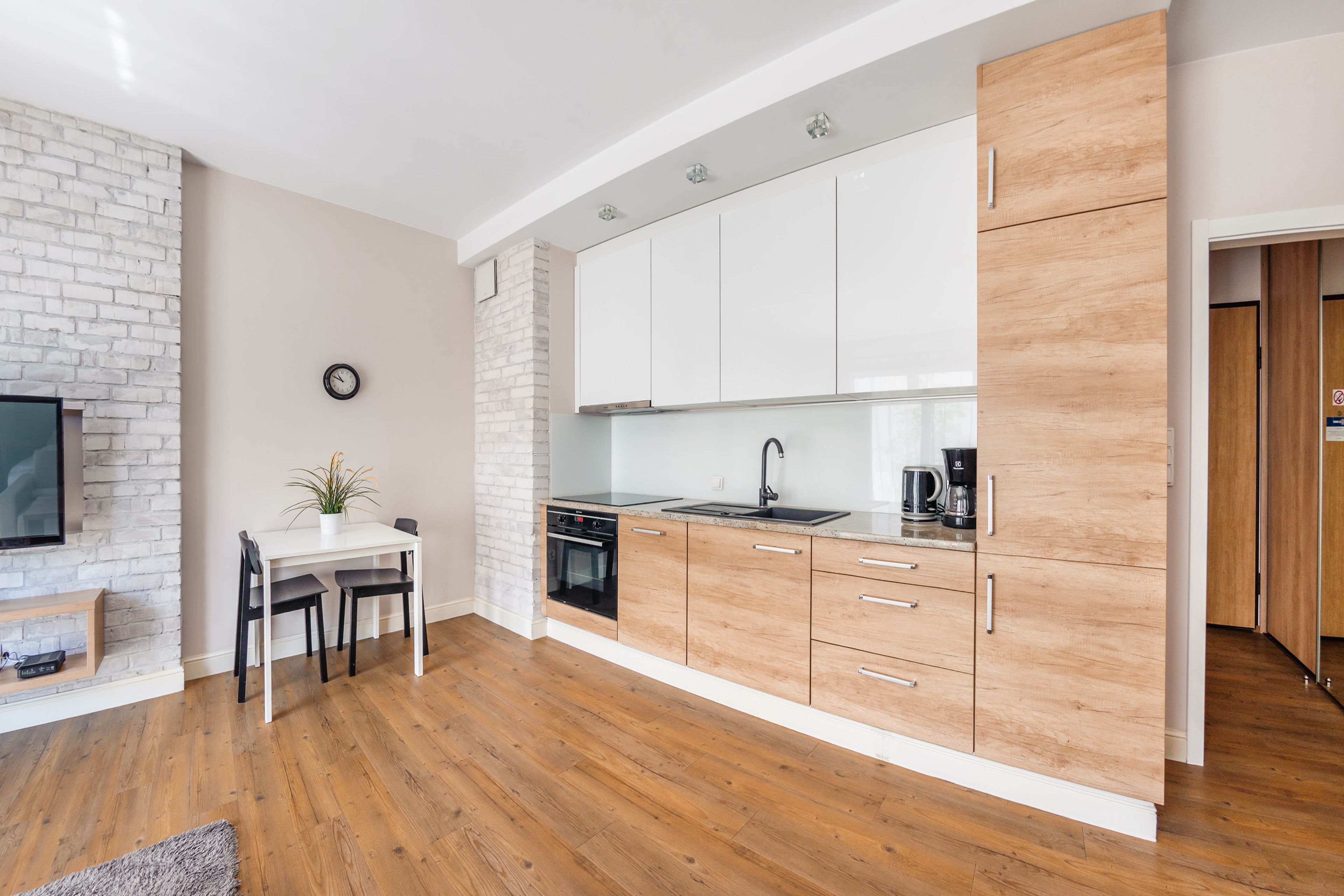Une cuisine moderne avec des meubles blancs, une cuisinière noire et une machine à café.