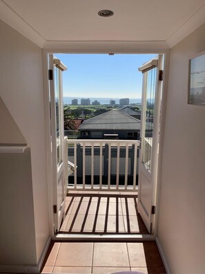A narrow hallway leading to a balcony with a view of a cityscape. - Cheviot Place Guest House (Cape Town)
