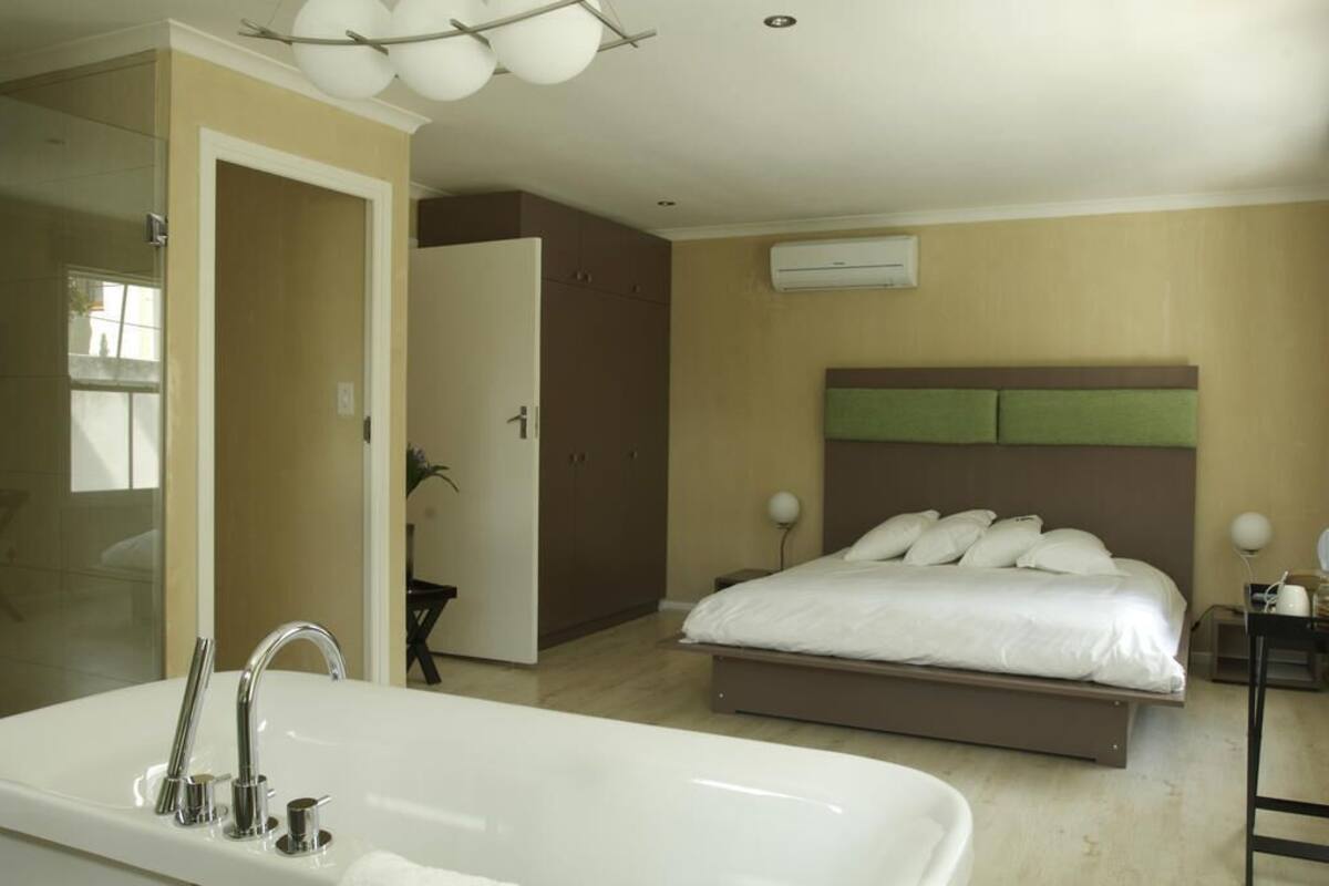 Un dormitorio moderno con una cama grande, un baño separado con bañera y un vestidor.