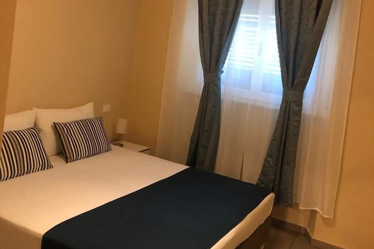A bedroom with a bed, curtains, and a hanging light fixture.