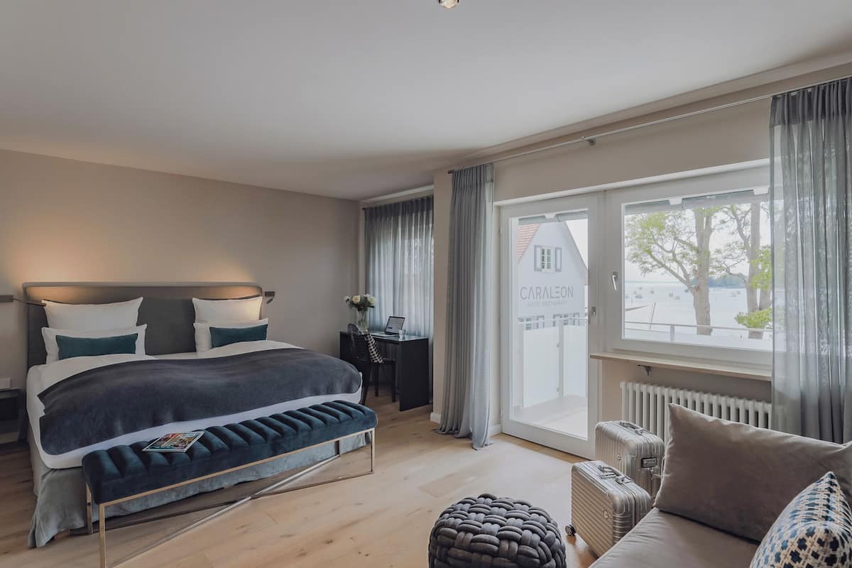 Ein modernes Hotelzimmer mit einem großen Bett, einem Schreibtisch, Blick ins Freie und einem mit Vorhängen versehenen Fenster.