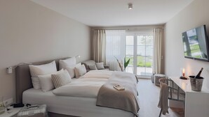Une chambre d’hôtel moderne avec un grand lit, un bureau avec une télévision et une vue sur l’extérieur.