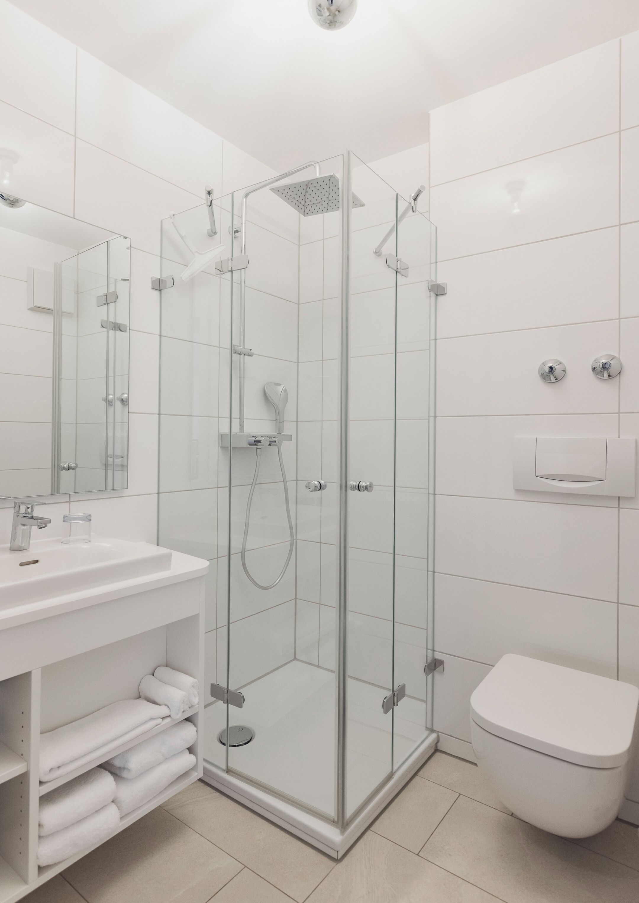 A modern bathroom with a glass-enclosed shower, a white sink, and a toilet.