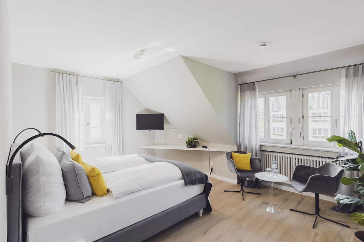Ein modernes, helles Zimmer mit einem Bett, einem Schreibtisch und einem Stuhl.