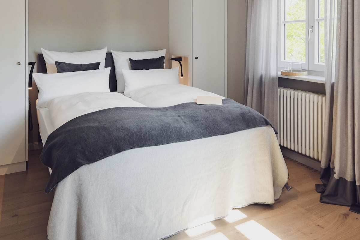 Ein Schlafzimmer mit einem Bett, einem Fenster mit Vorhängen und einer Heizung.