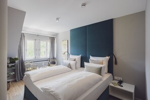 Un dormitorio moderno con una cama grande, una mesita de noche, una silla y una ventana con cortinas.