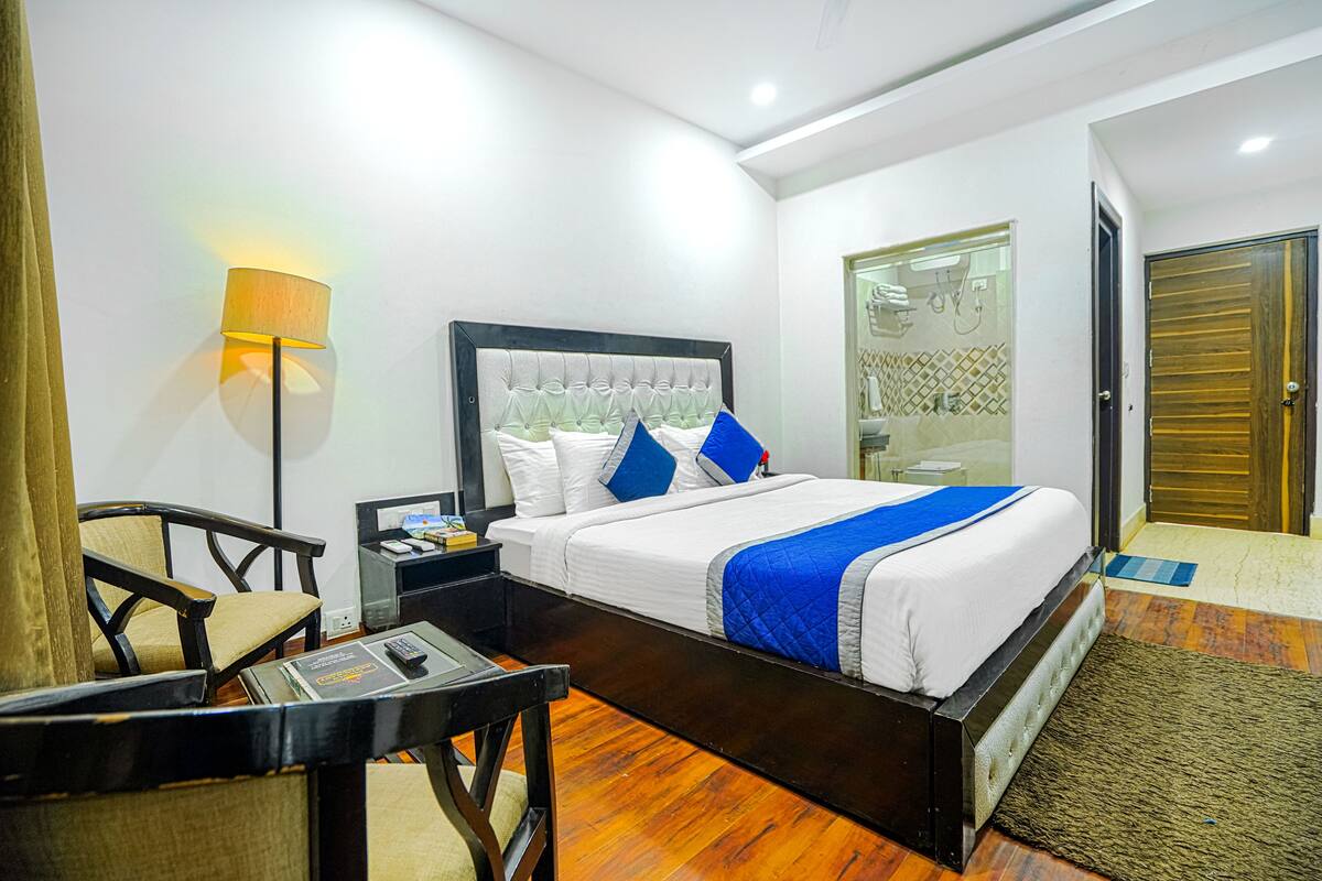 Una habitación de hotel con cama, escritorio, silla, lámpara y armario.