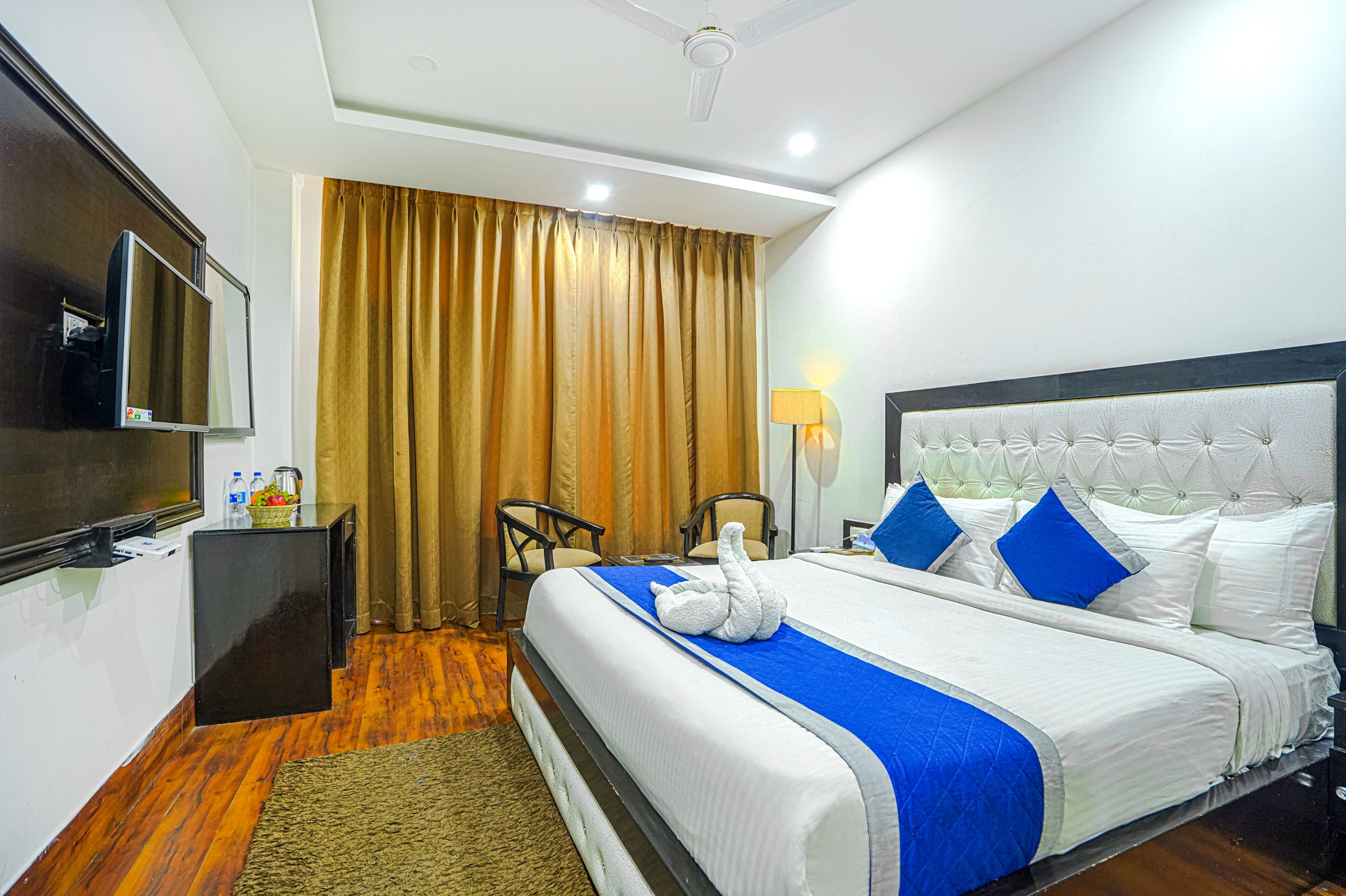 A hotel room with a bed, a television, a desk, and a chair.