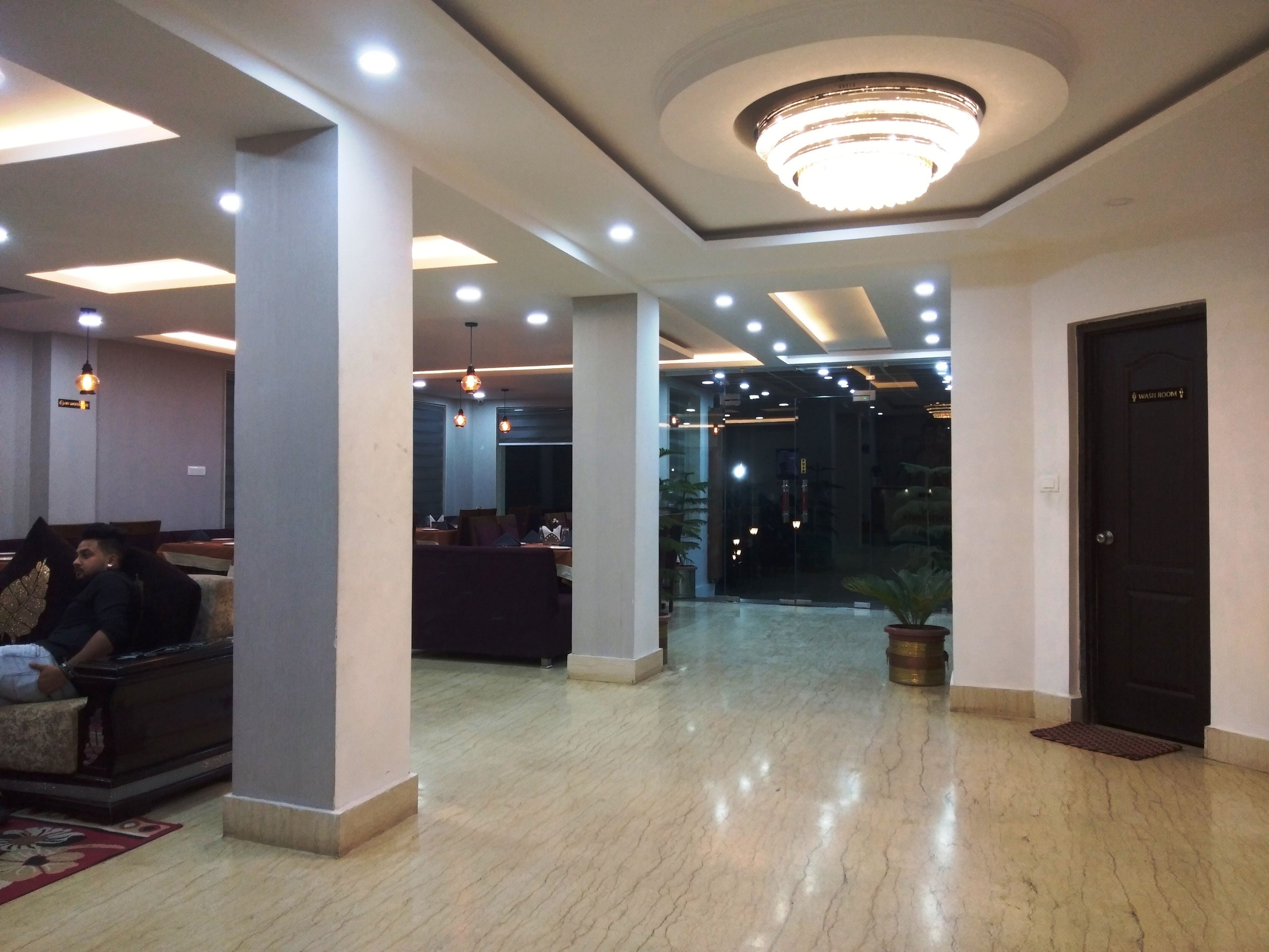 A hotel lobby with a reception desk, seating area, and a washroom.