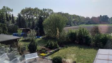Una zona residencial con jardín, un estanque pequeño y un campo al fondo.