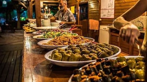 Una mesa de buffet con diversos platos, como verduras rellenas y ensaladas, en un ambiente rústico de cabaña.