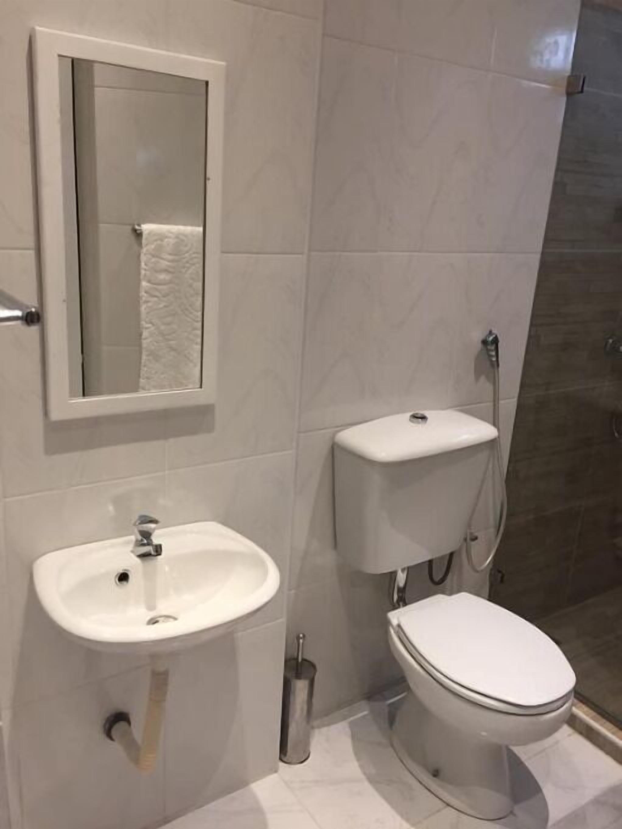 A bathroom with a white sink, toilet, and shower.