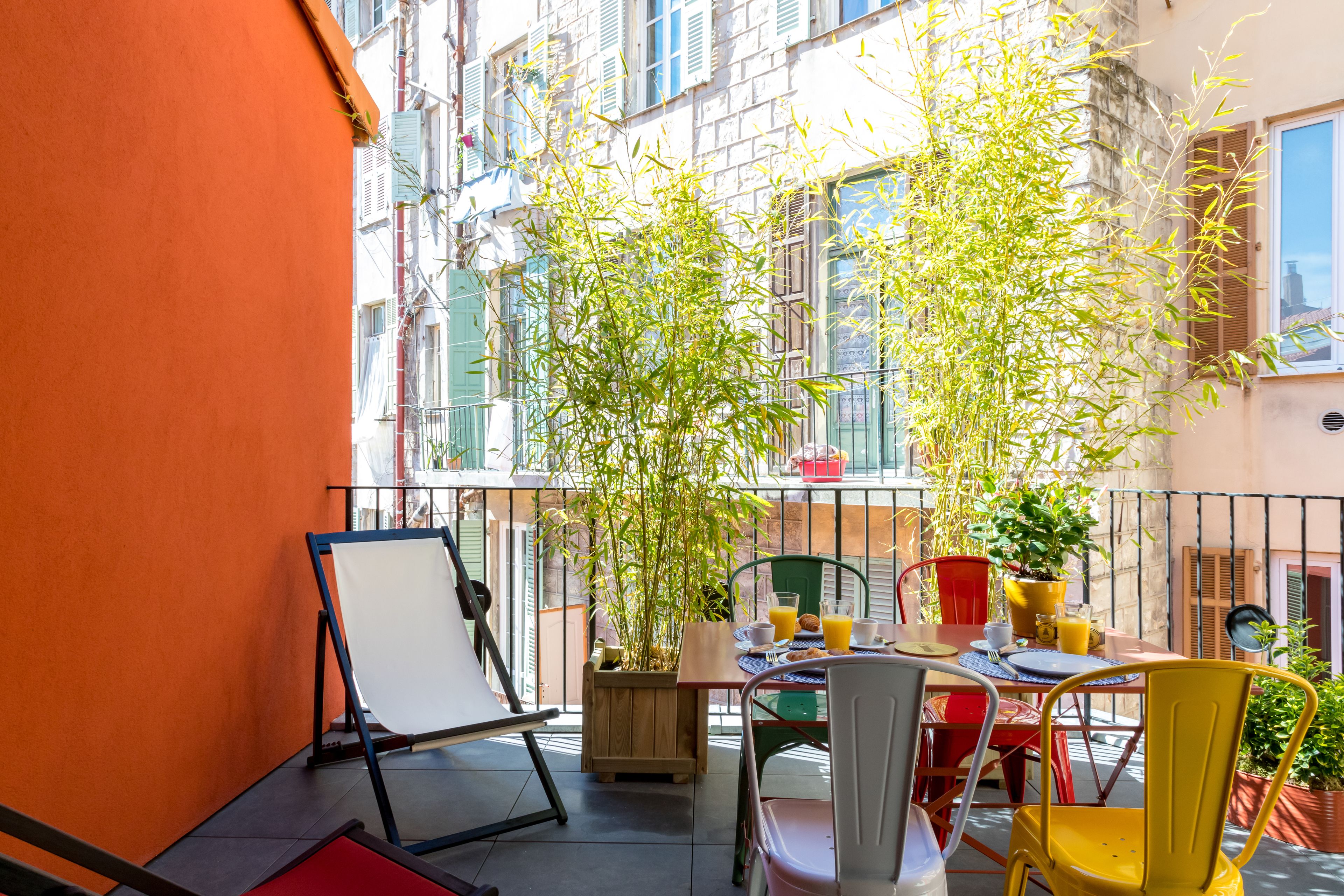 A balcony with a dining table, chairs, and potted plants.