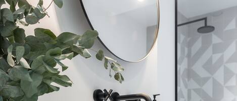 Un bagno con un lavandino bianco, uno specchio e una zona doccia.