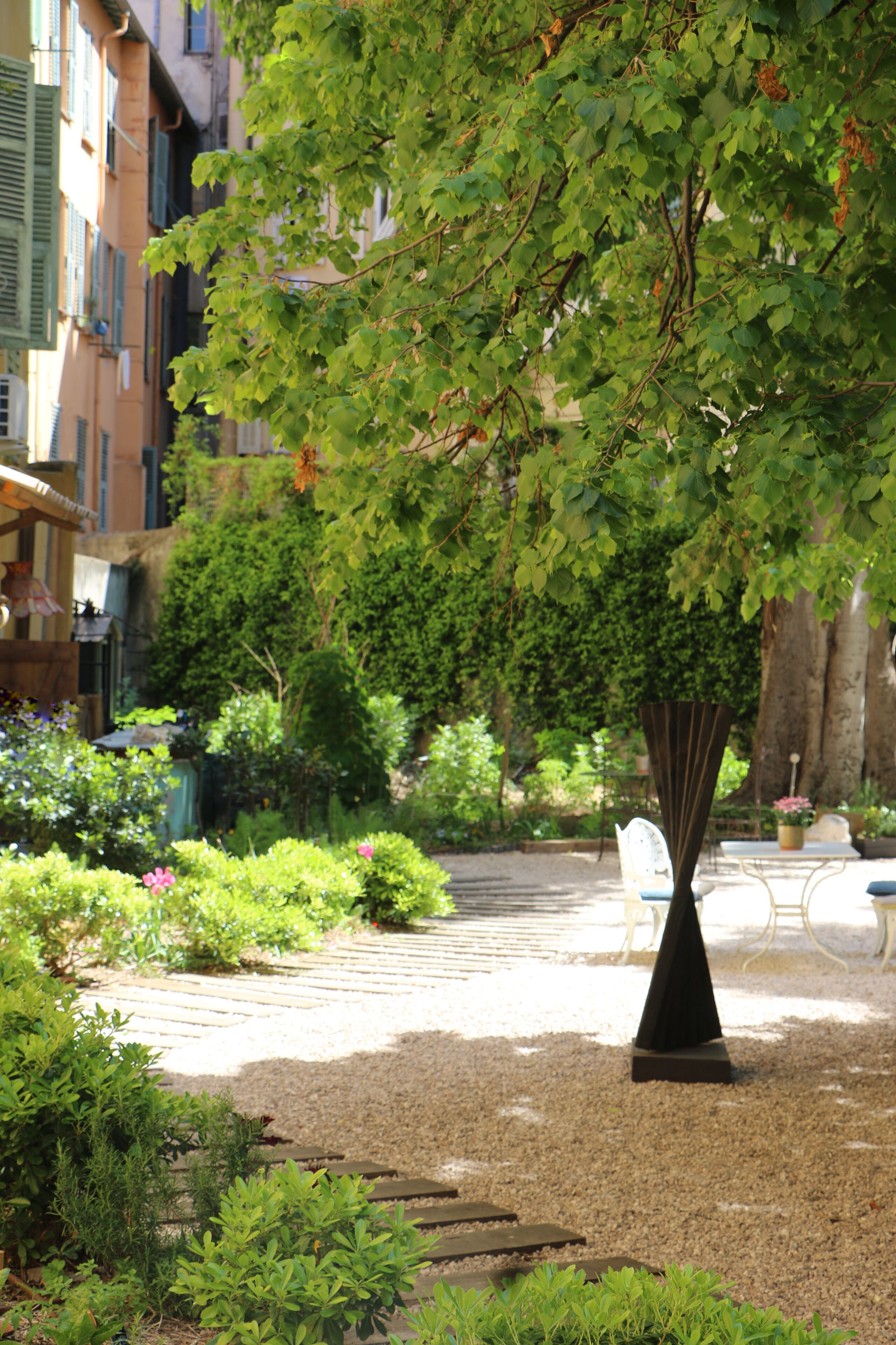 Um jardim com uma árvore, caminhos de cascalho e móveis de exterior.