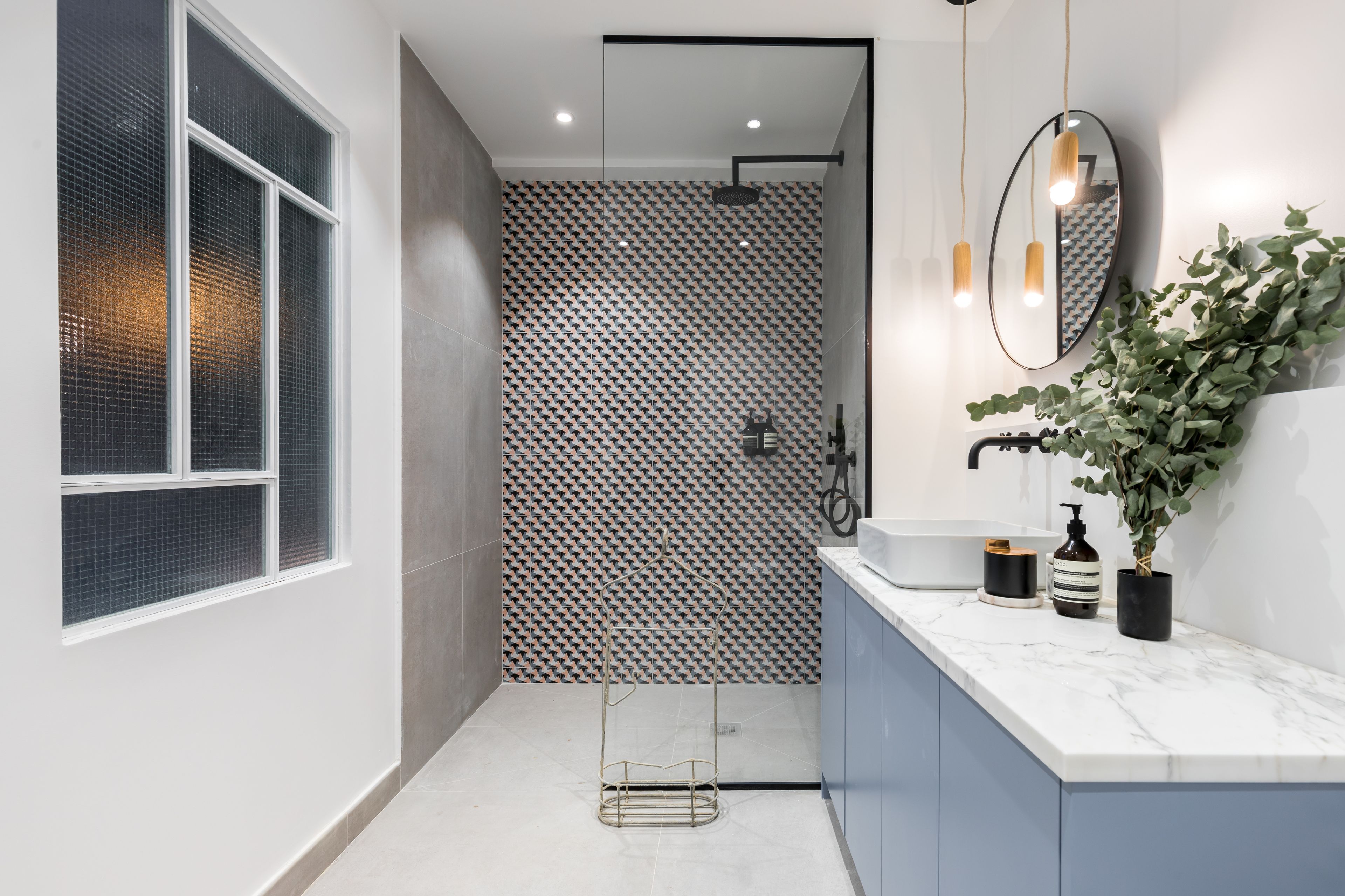 A modern bathroom with a shower, a large window, and a marble countertop.