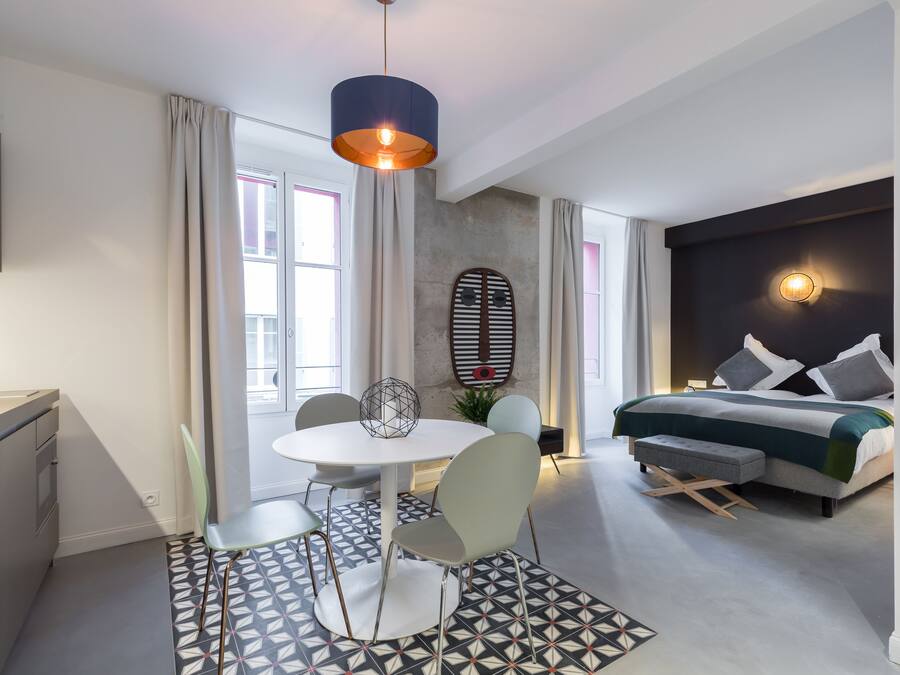 Une chambre d’hôtel moderne dotée d’un coin repas, d’un lit avec une tête de lit et d’une grande fenêtre.