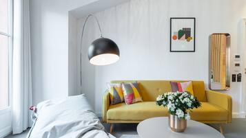 A modern living room with a yellow sofa, a round coffee table, and a hanging black pendant light.