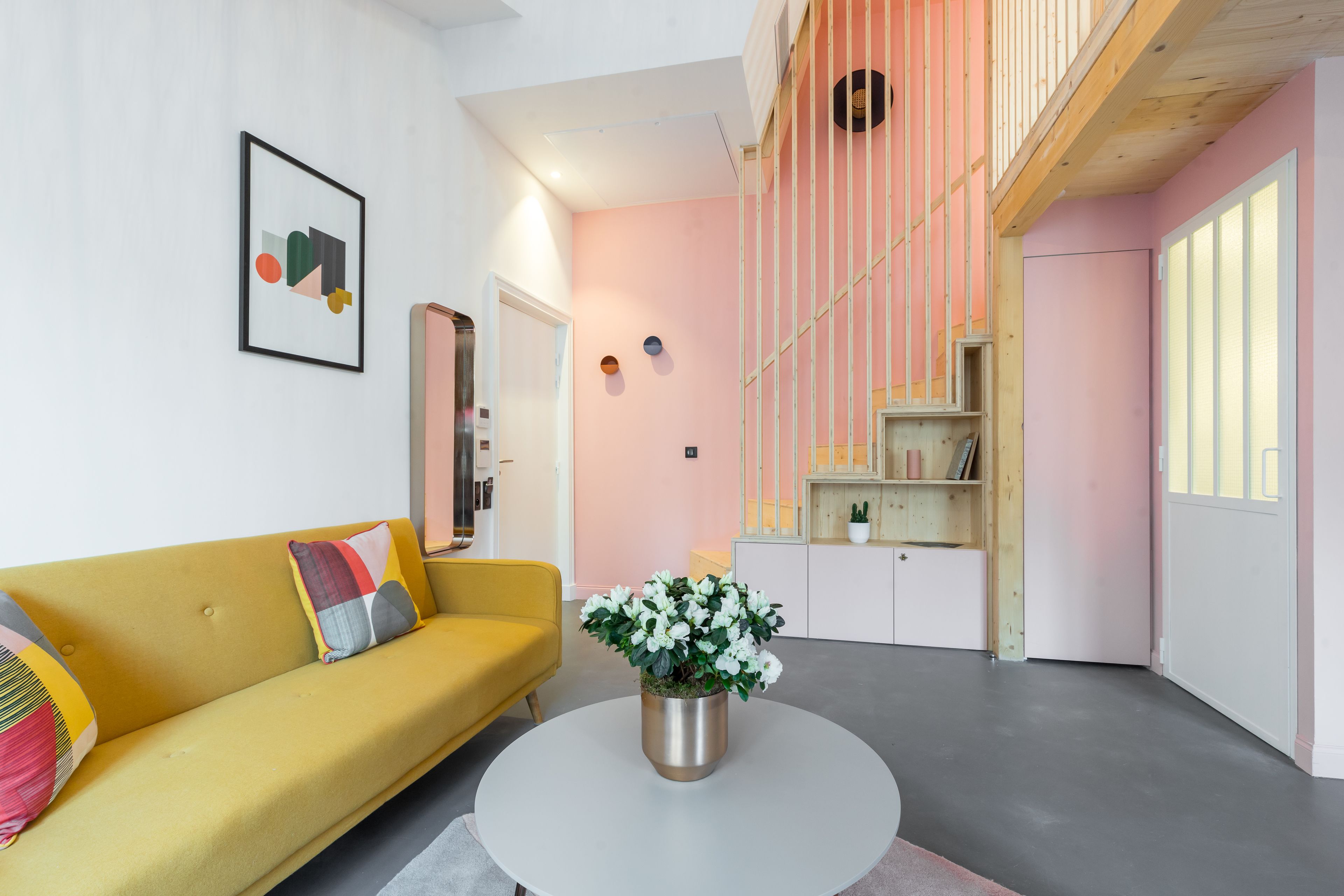 A modern living room with a yellow sofa, a white coffee table, and a potted plant.