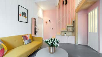 A modern living room with a yellow sofa, a white coffee table, and a potted plant.