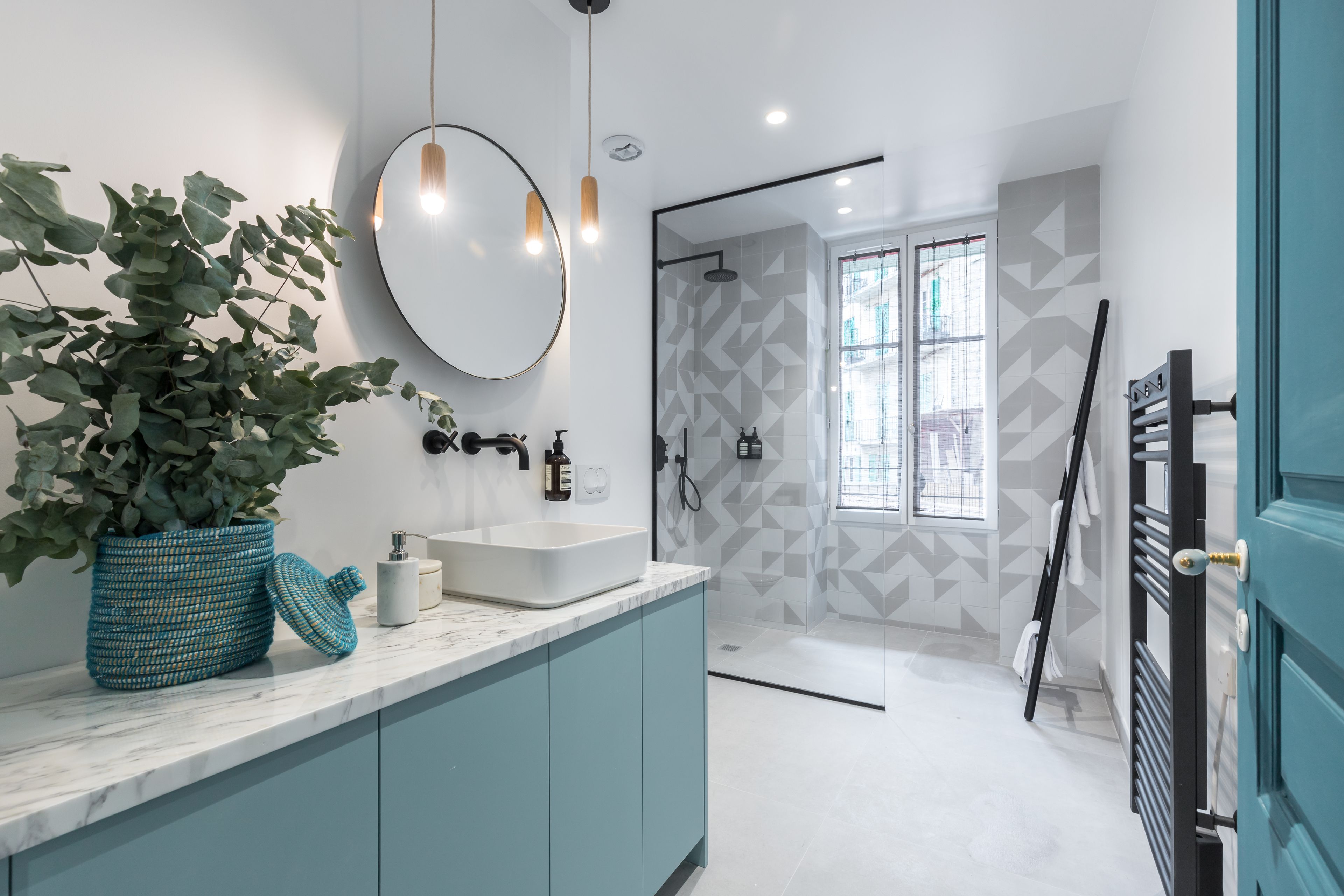 A modern bathroom with a large mirror, a sink, and a shower area.