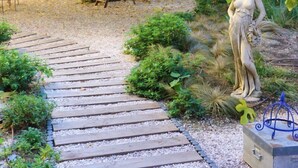 A garden pathway leading to a statue, surrounded by greenery and a large tree. - L'Abeille Boutique Apartments (Nice)