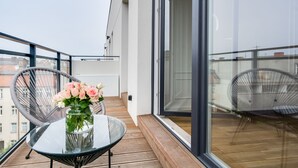 Ein Balkon mit Glastisch, einem Stuhl und einem Blumenstrauß.