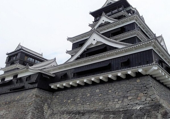 Eine traditionelle japanische Burg mit mehreren Ebenen, Steinmauern und aufwendiger weißer und schwarzer Dachdeckung.