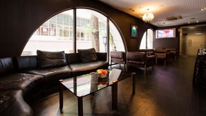 A modern lounge with leather seating, a glass coffee table, and large windows. - Hotel Okus Kumamoto (Kumamoto)