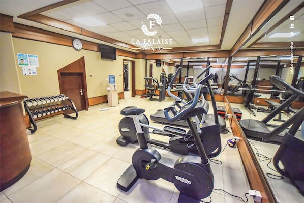 A gym with various exercise equipment including treadmills, ellipticals, and a weight bench. - Hotel La Falaise Bonapriso (Douala)