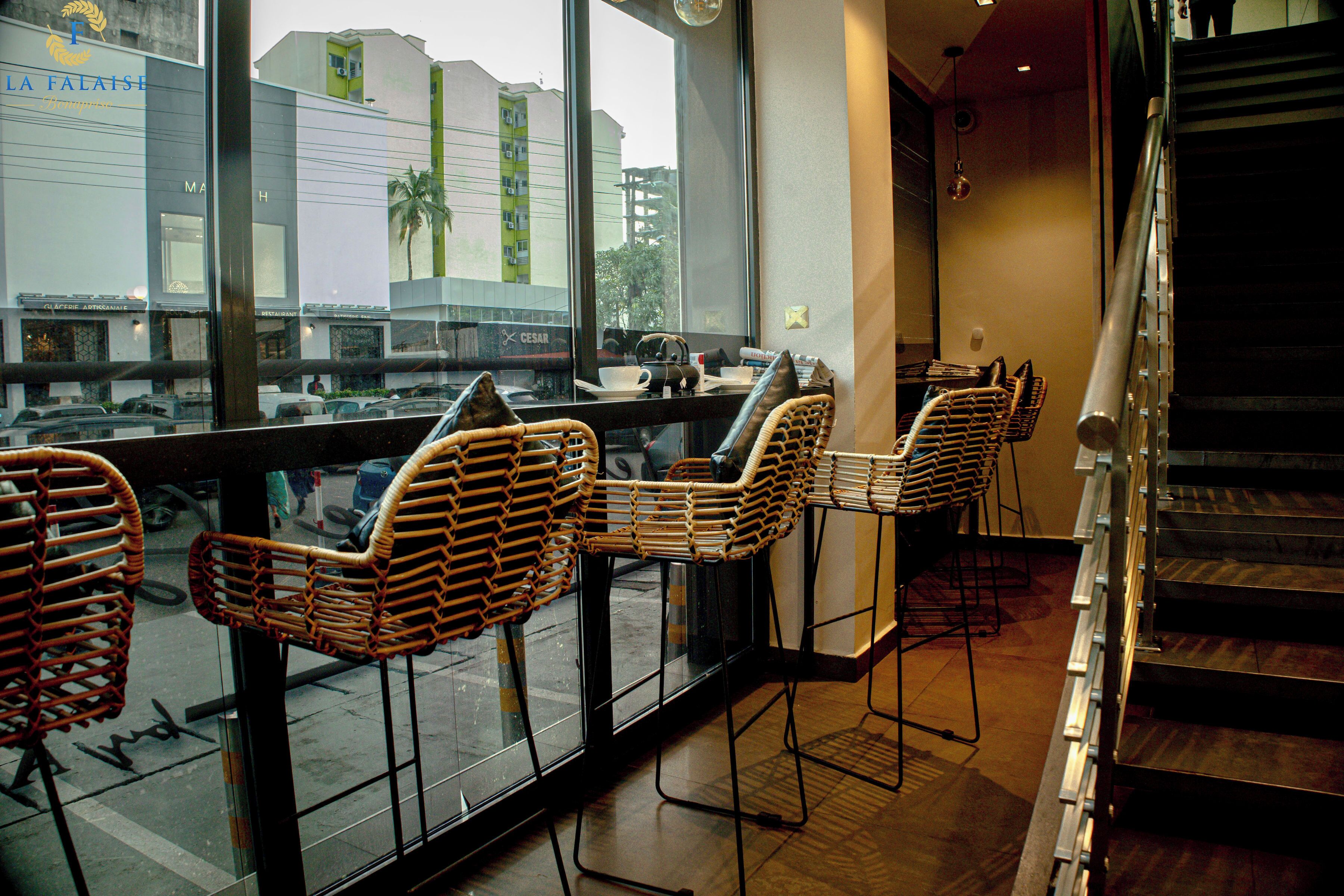 Un restaurant avec des chaises en osier, un escalier et une vue sur la rue.