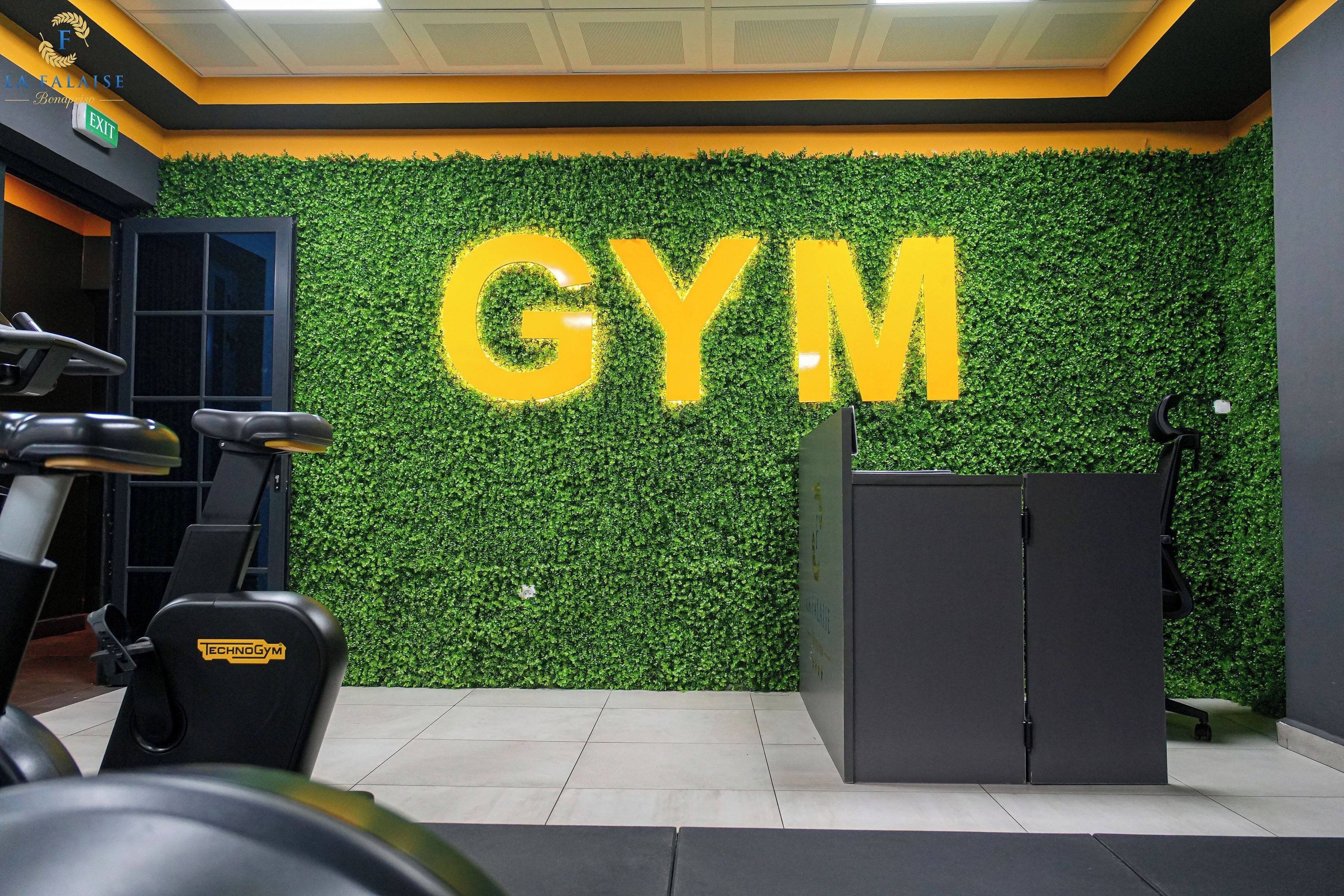 Un gimnasio con una pared verde y la palabra 'GYM' en letras grandes.